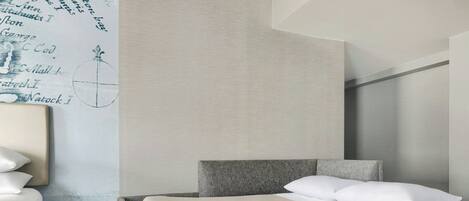 Een moderne hotelkamer met een bed, een stoel, een klein tafeltje en een wand met een decoratieve kaart.