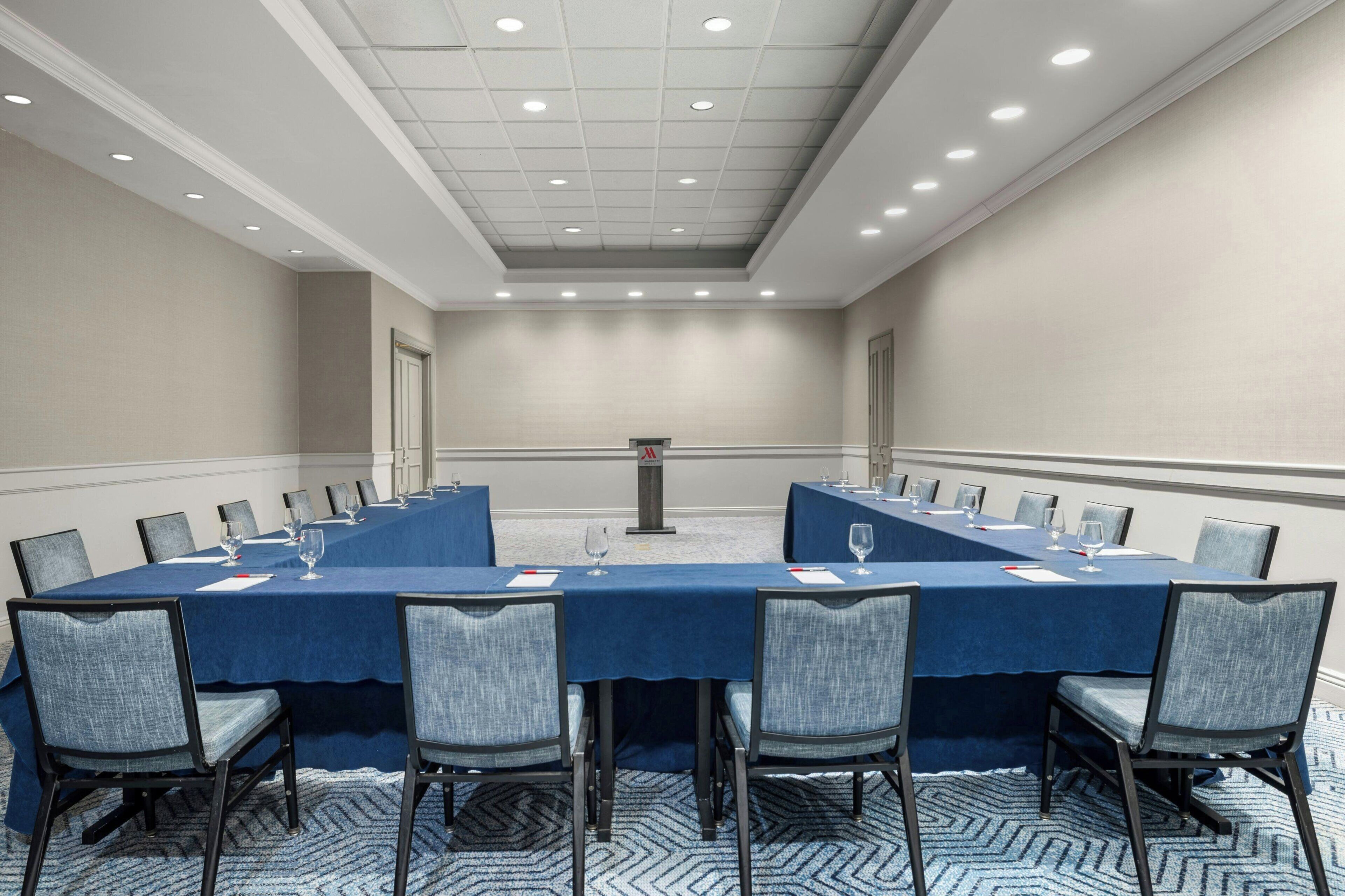 Une salle de conférence avec une longue table, des chaises et un pupitre.