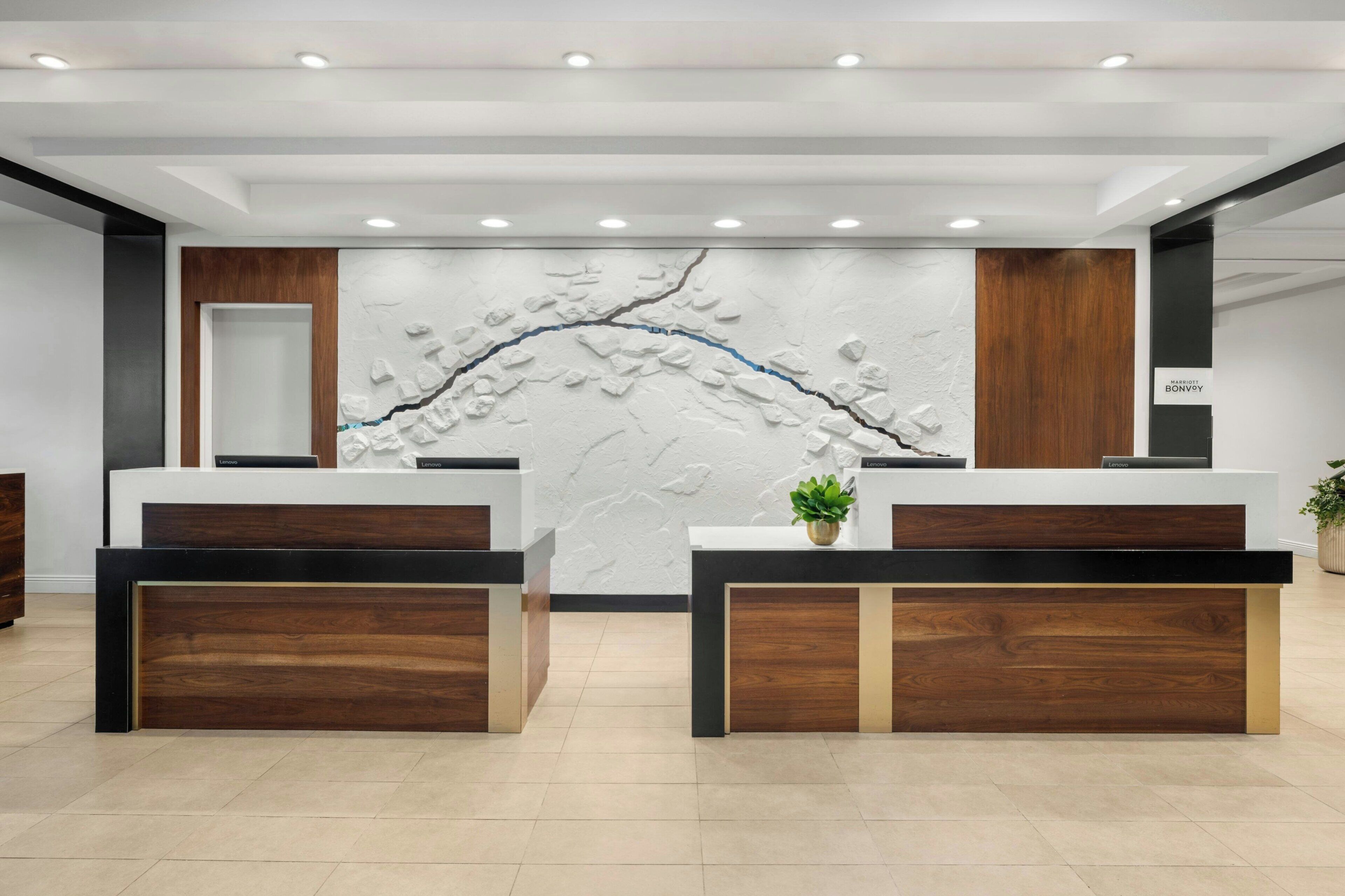 A modern reception area with two reception desks, a textured wall feature, and a wooden panel design.