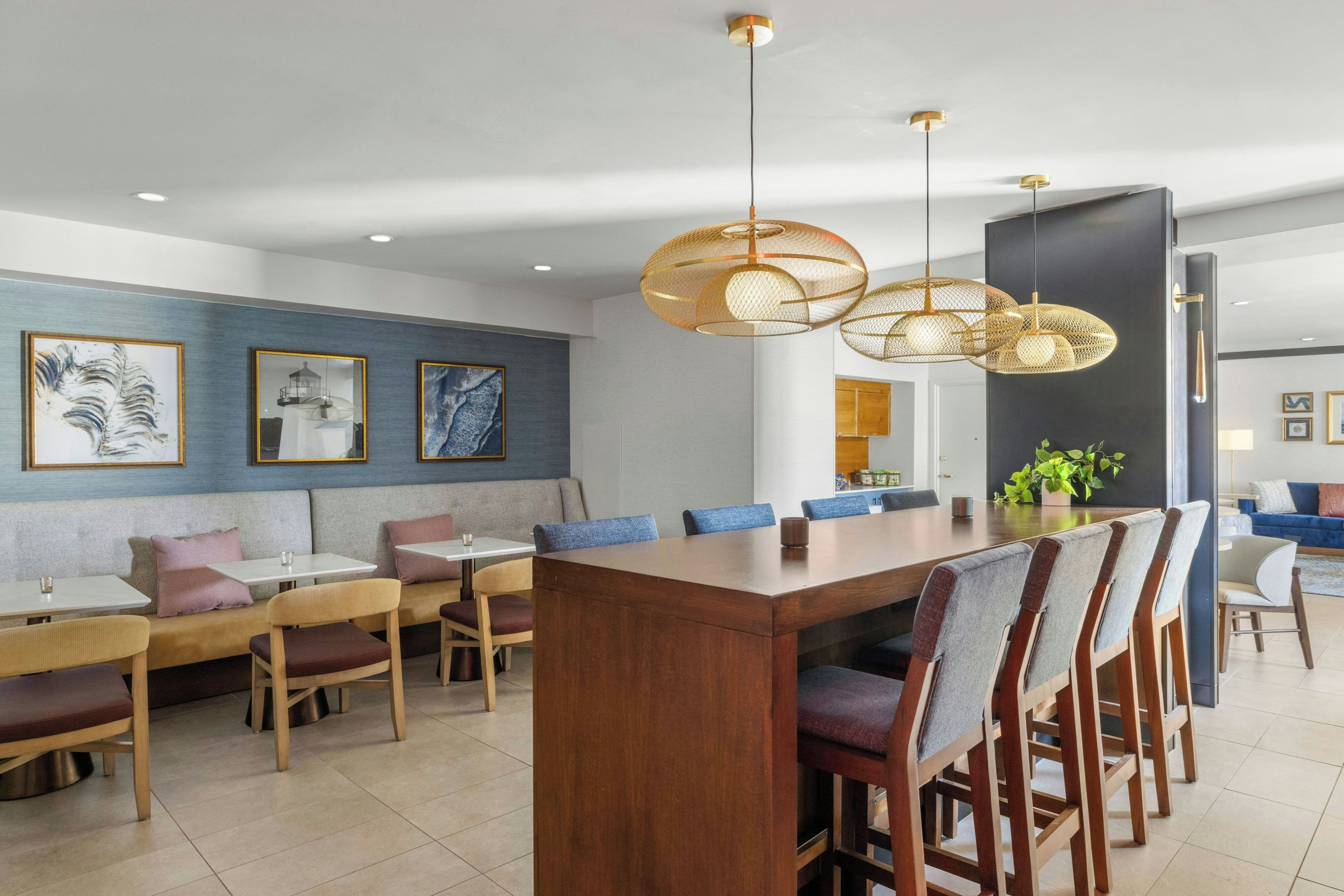 A modern dining area with a wooden table and chairs, a blue wall with artwork, and pendant lighting.