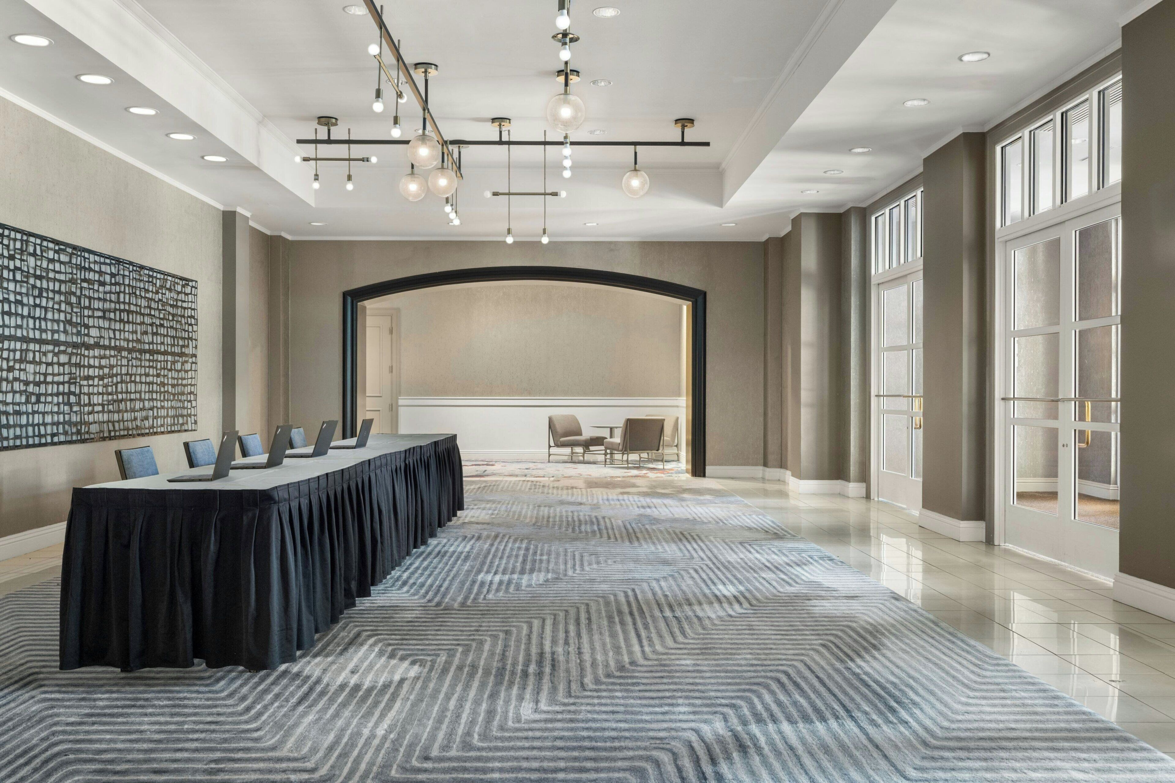 A conference room with a long table, chairs, and a patterned carpet.