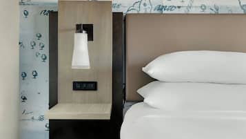 Una habitación de hotel con una cama, una mesita de noche con una lámpara y un papel tapiz con motivos florales.