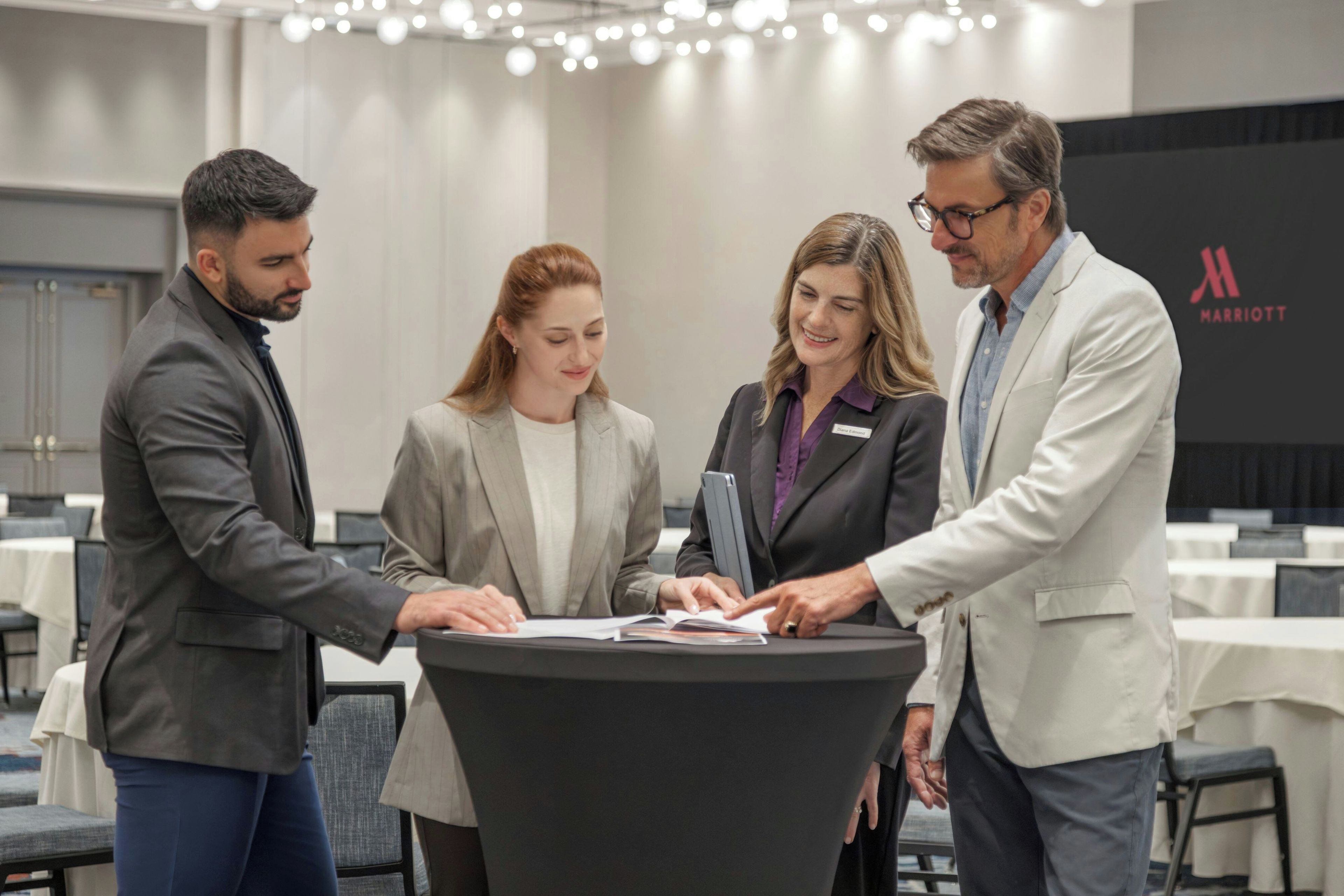 A group of four people at a conference table in a hotel setting with a Marriott logo.