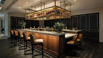A bar area with a long counter, multiple stools, and a ceiling-mounted liquor display.