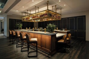 A bar area with a long counter, multiple stools, and a ceiling-mounted liquor display. - Mystic Marriott Hotel and Spa (Groton)