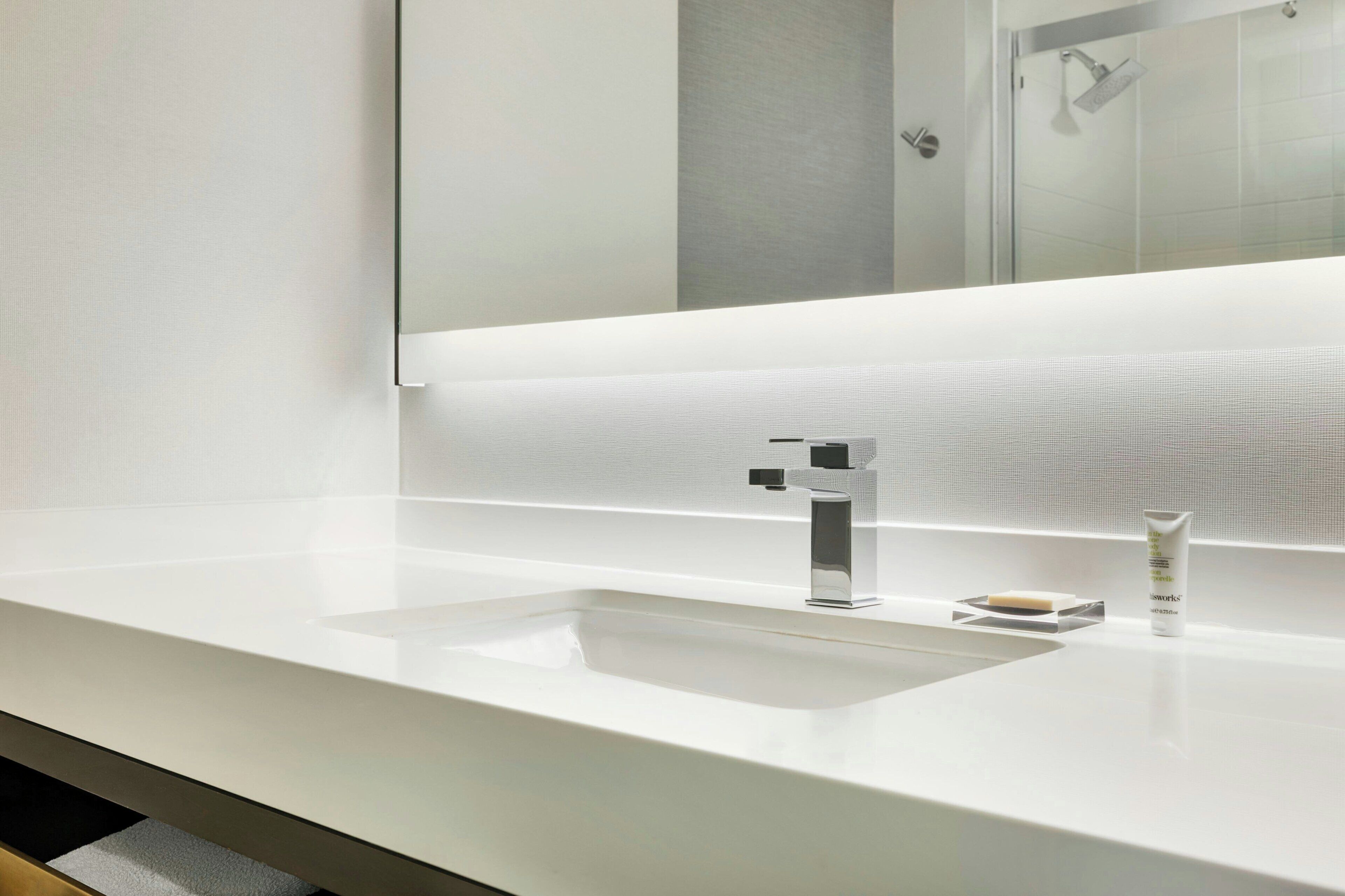 Une salle de bain moderne avec un lavabo blanc, un miroir et un espace douche.