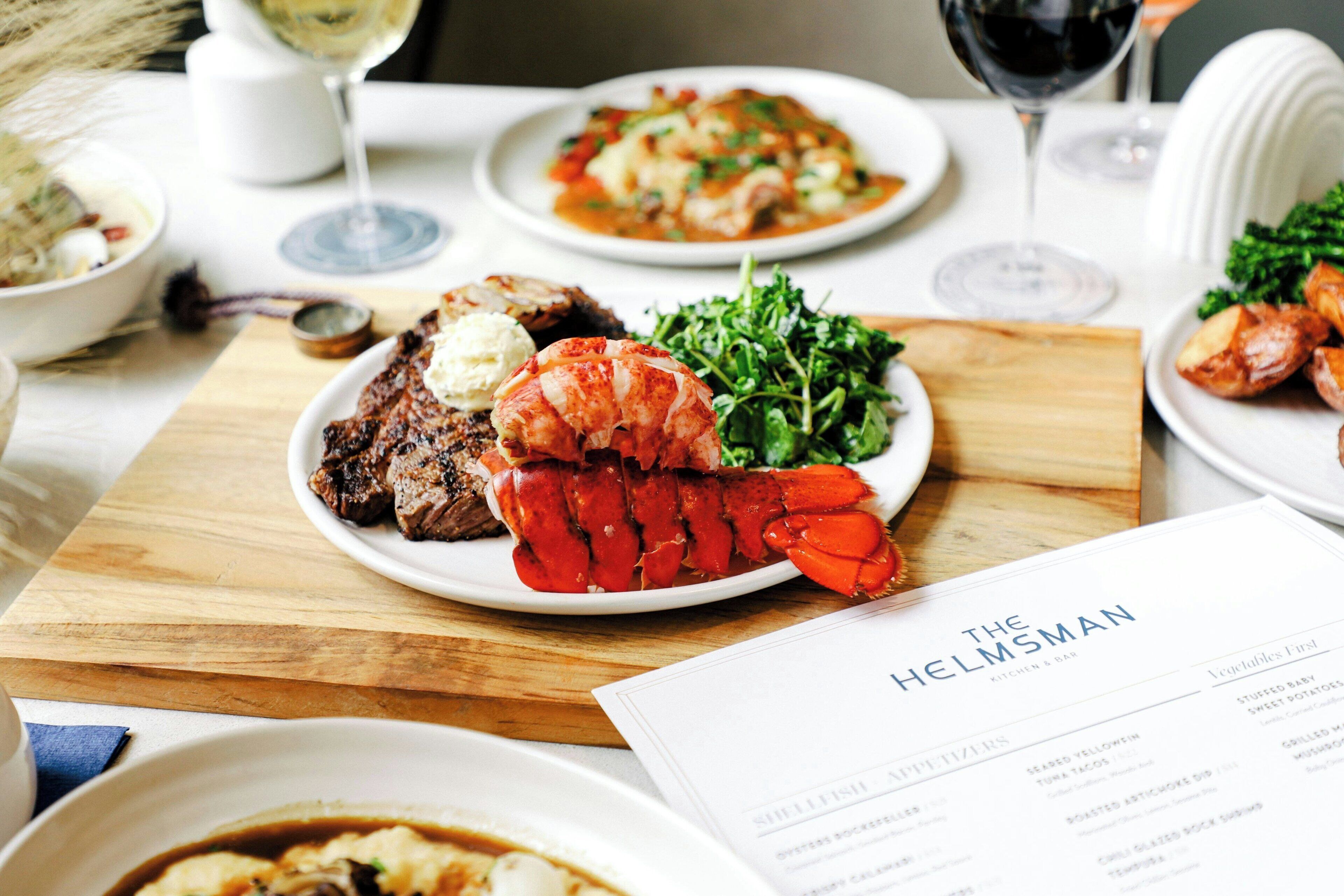Une table à manger avec différents plats, un menu et des verres à vin.