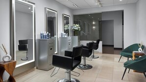 A modern salon with mirrored walls, black salon chairs, and a clean, tiled floor. - Mystic Marriott Hotel and Spa (Groton)