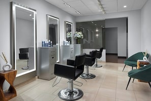 Un salon moderne avec des murs recouverts de miroirs, des fauteuils noirs et un sol carrelé, propre et élégant.