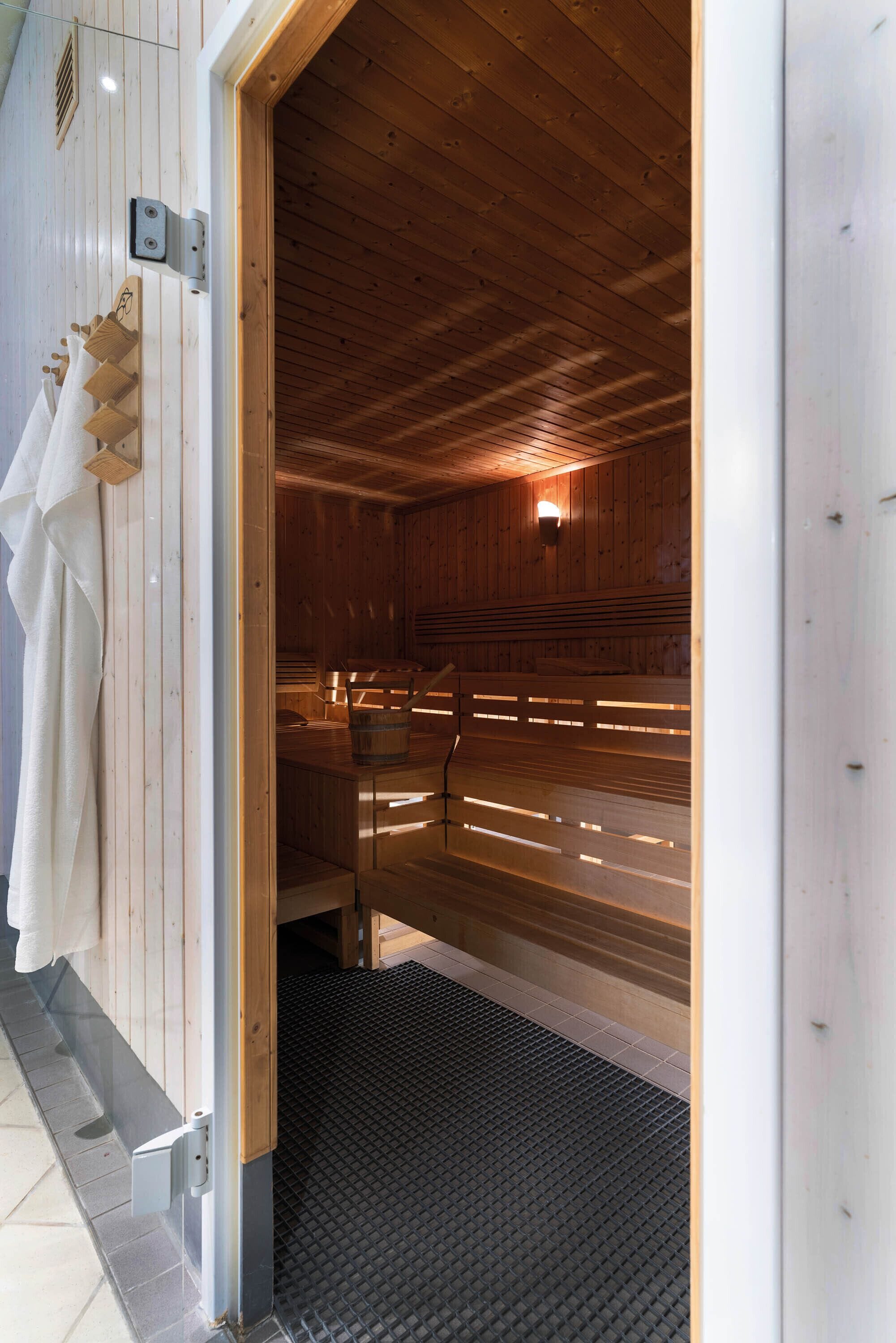 Una sala de sauna con bancos de madera y piso de baldosas.