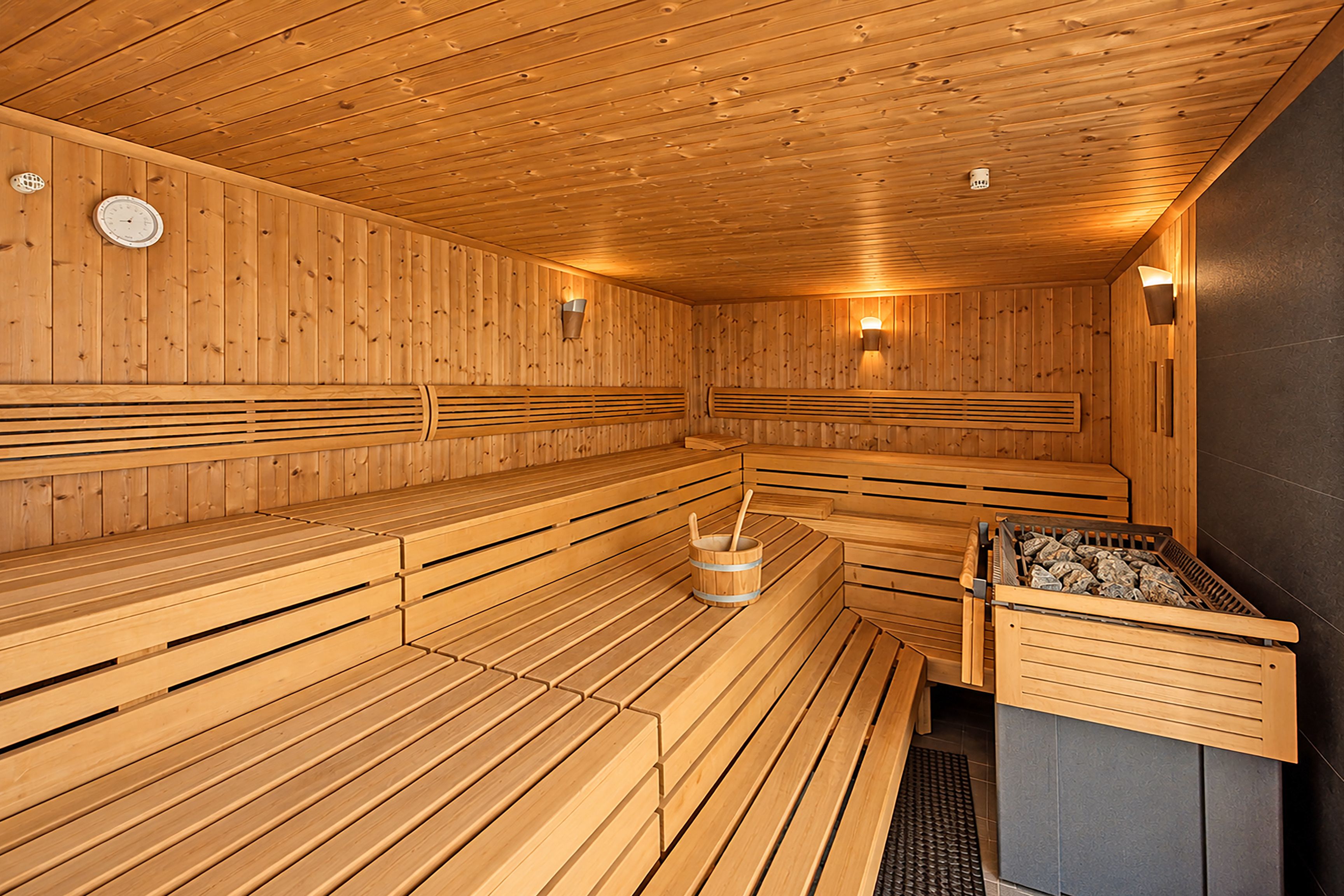 Uma sauna com bancos de madeira e um elemento de aquecimento de pedra.