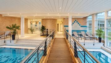 Eine Hotelhalle mit Poolbereich, ausgestattet mit einer Holztreppe, Geländern und Blumentöpfen.