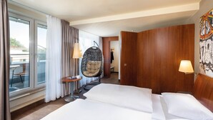 A hotel room with a large bed, a hanging chair, a small table, and a view of the outdoors. - Seminaris Seehotel Potsdam (Potsdam)