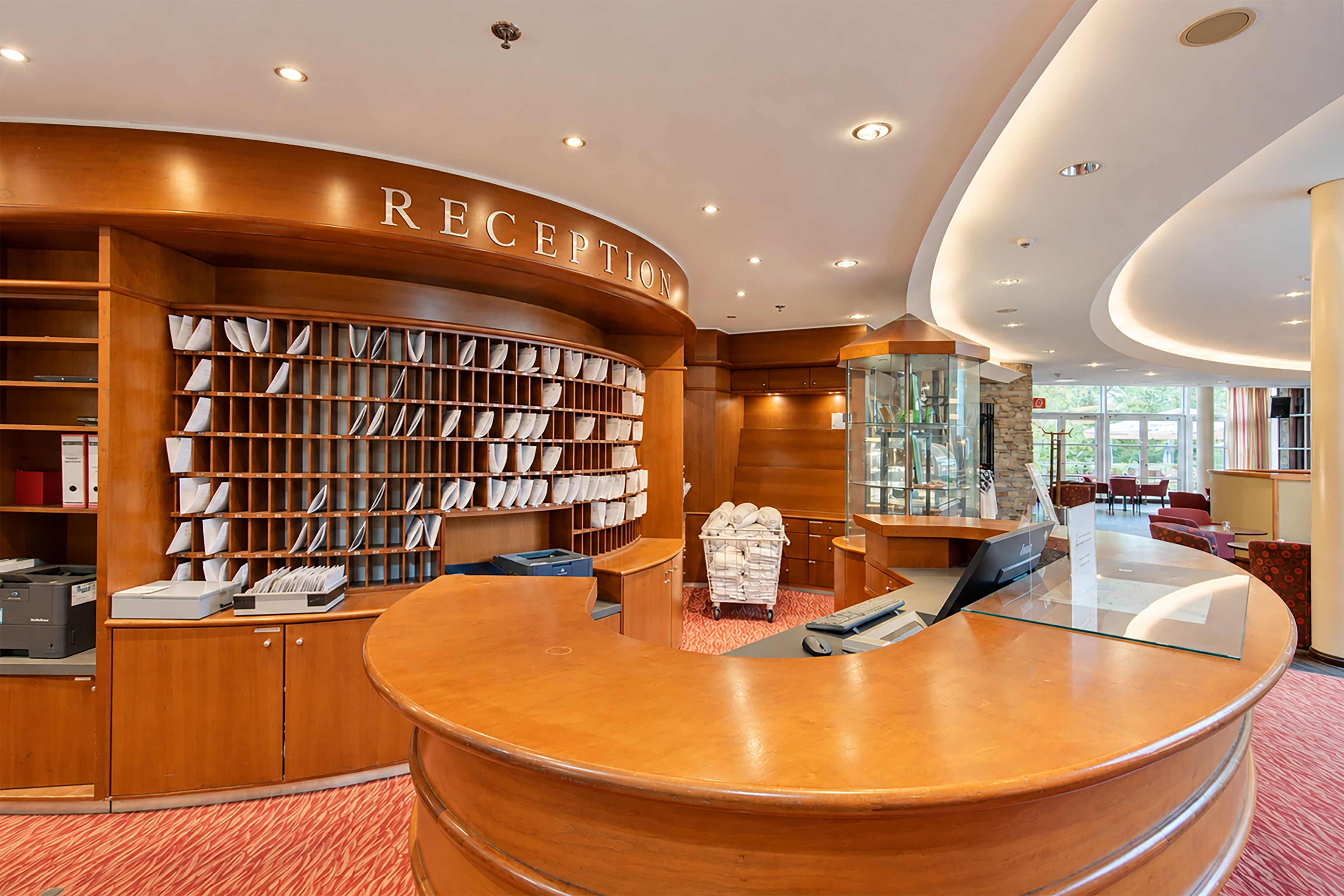 A reception area with a wooden reception desk, a large bookcase filled with books, and a glass display case.