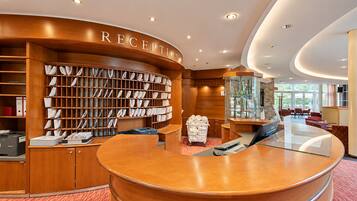 Ein Empfangsbereich mit einem Holzbüro, einem großen Bücherregal voller Bücher und einer Glastheke.
