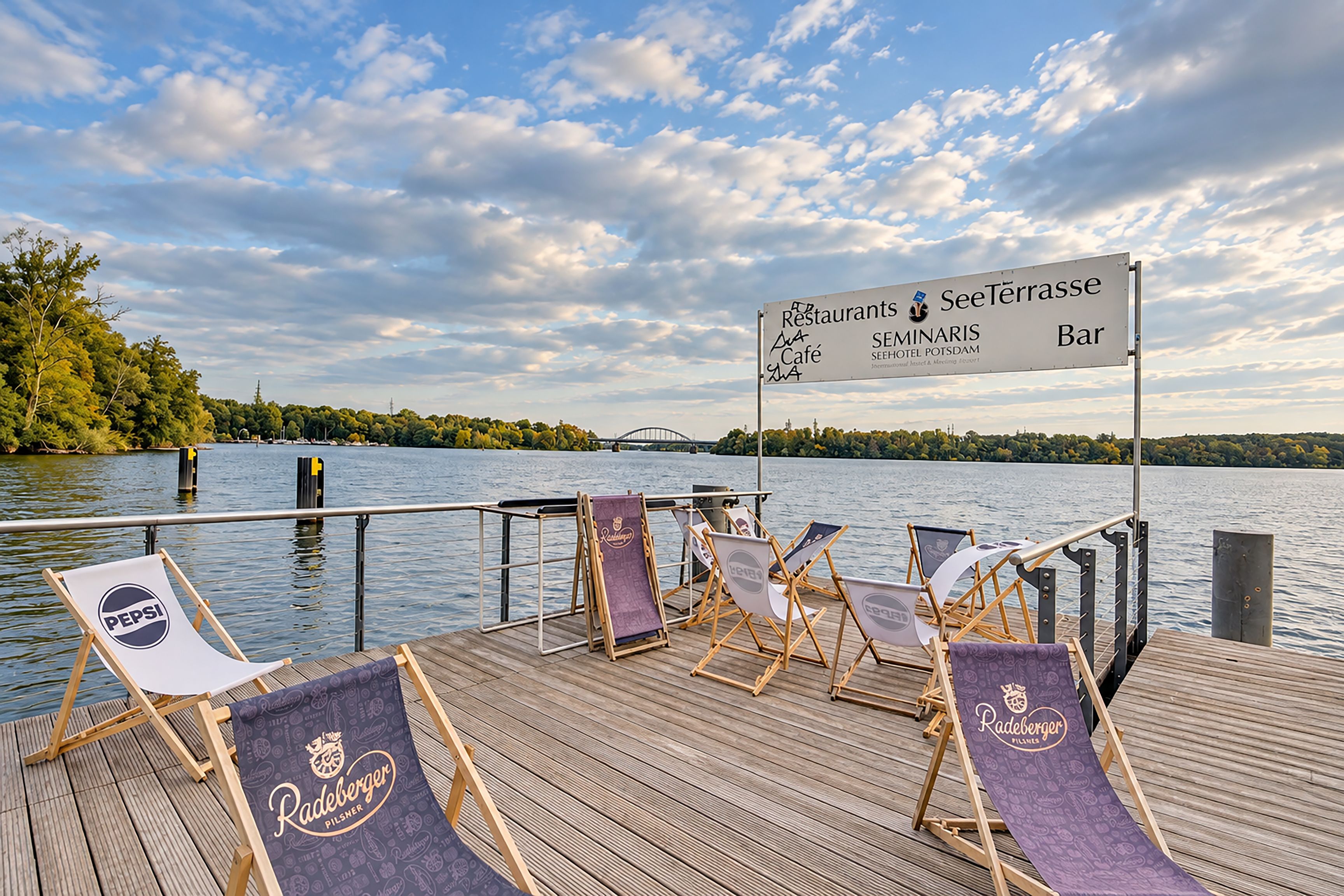 Un patio in legno con poltrone relax e un cartello che indica servizi come ristoranti, una terrazza, un caffè e un bar.