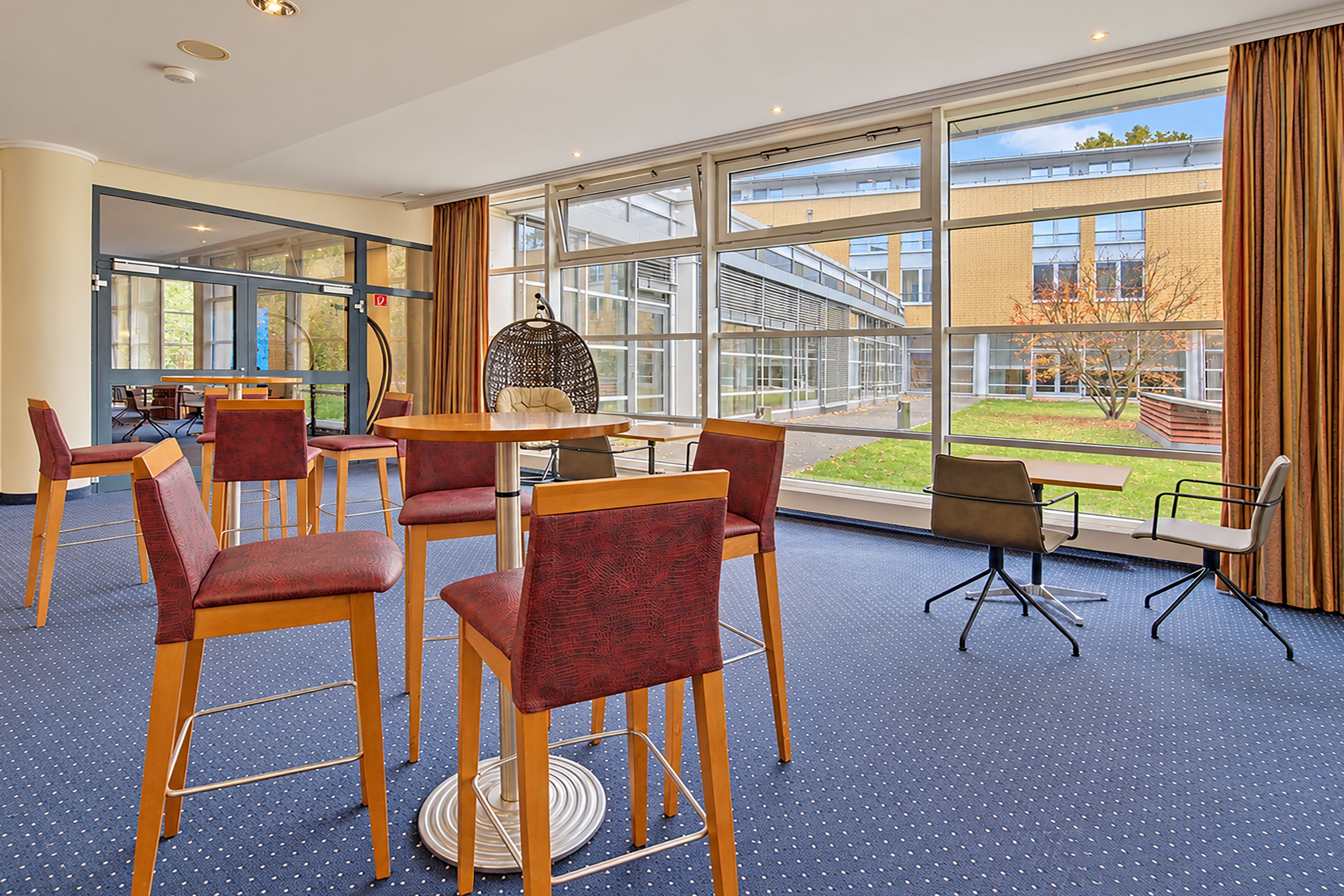 A conference room with a large window, a round table, and several chairs.