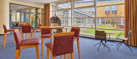 A conference room with a large window, a round table, and several chairs.