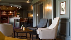 Un área de estar moderna con un bar al fondo, que ofrece asientos cómodos e iluminación ambiental.