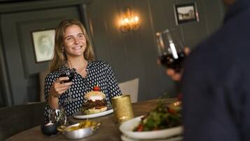 A dining table with a burger, salad, and wine glasses.