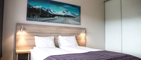 A bedroom with a bed, a nightstand, a wall-mounted painting, and a sliding closet door.