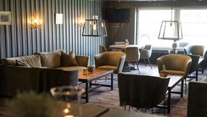 Un moderno vestíbulo de hotel con un sofá, sillas, una mesa de centro y un televisor montado en la pared.