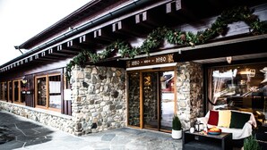 Un edificio de piedra con fachada de madera, un letrero que indica que fue construido en 1880 y una entrada de cristal.