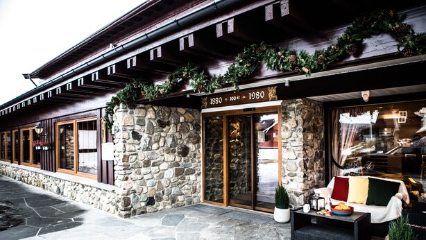 A stone building with a wooden facade, a sign indicating it was built in 1880, and a glass entrance.