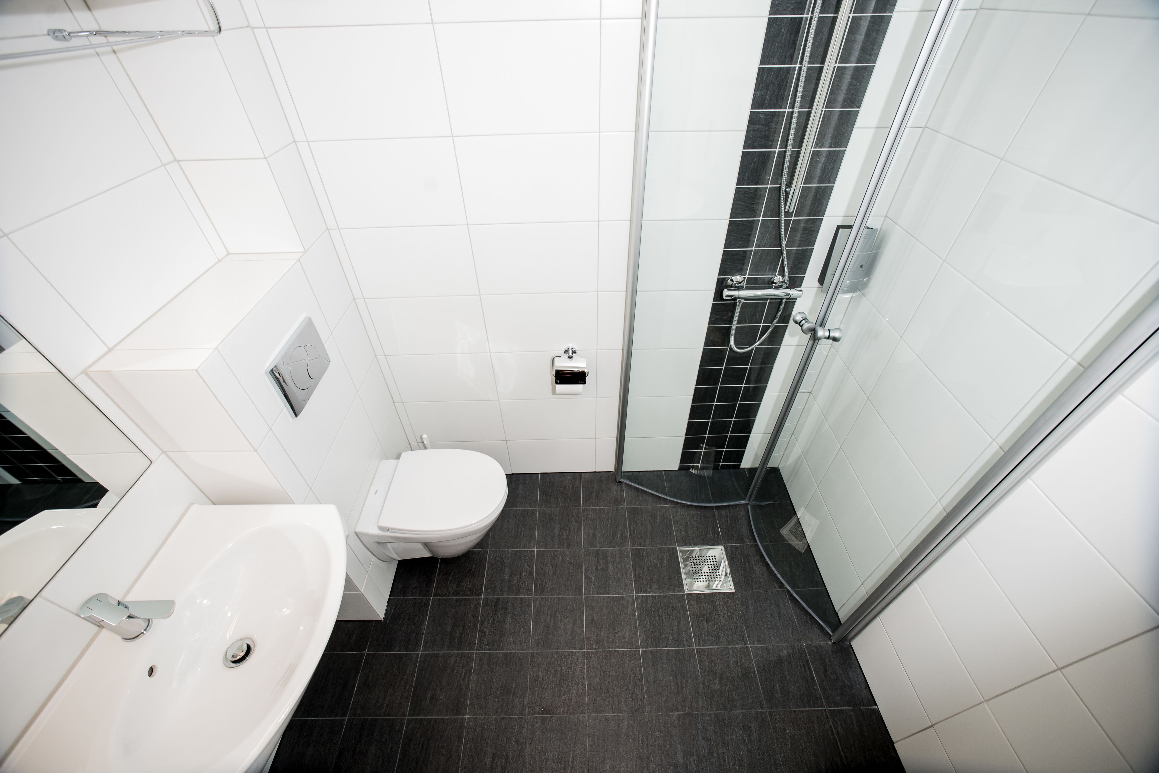 A modern bathroom with a white sink, toilet, and shower area.
