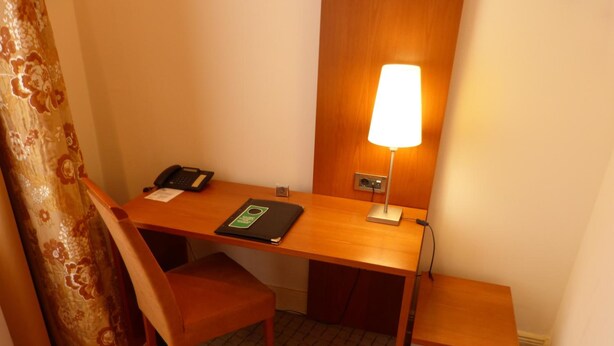 A small, neatly arranged workspace with a desk, chair, lamp, and a telephone. - Hotel Vorbach (Hamburg)