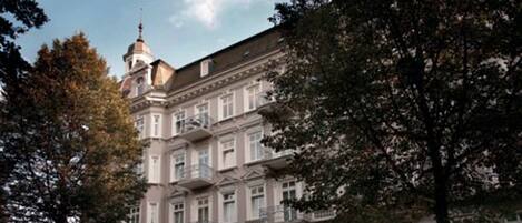 A multi-story building with a classical architectural style, featuring a prominent tower and multiple balconies.