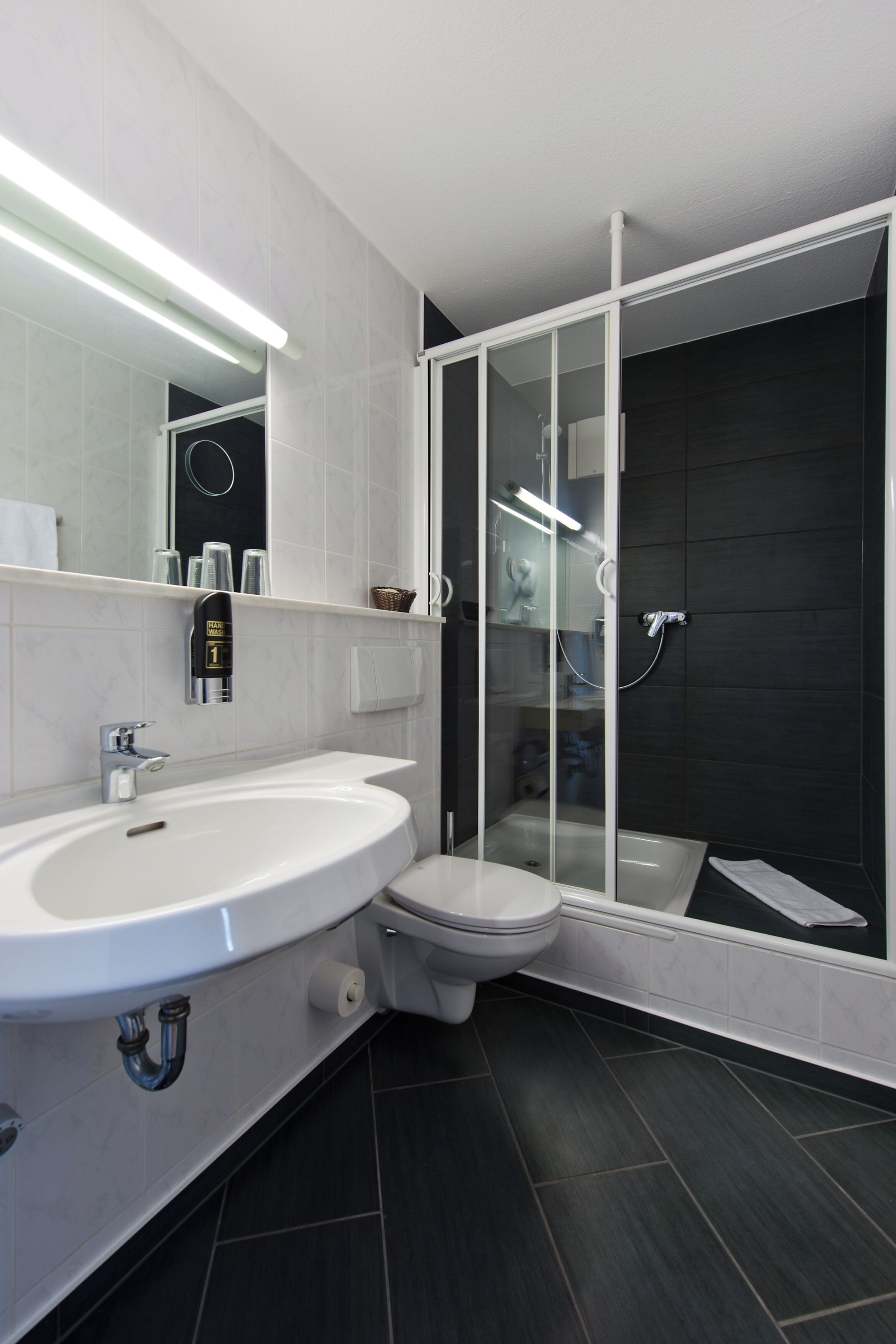 A modern bathroom with a white sink, toilet, and glass-enclosed shower.