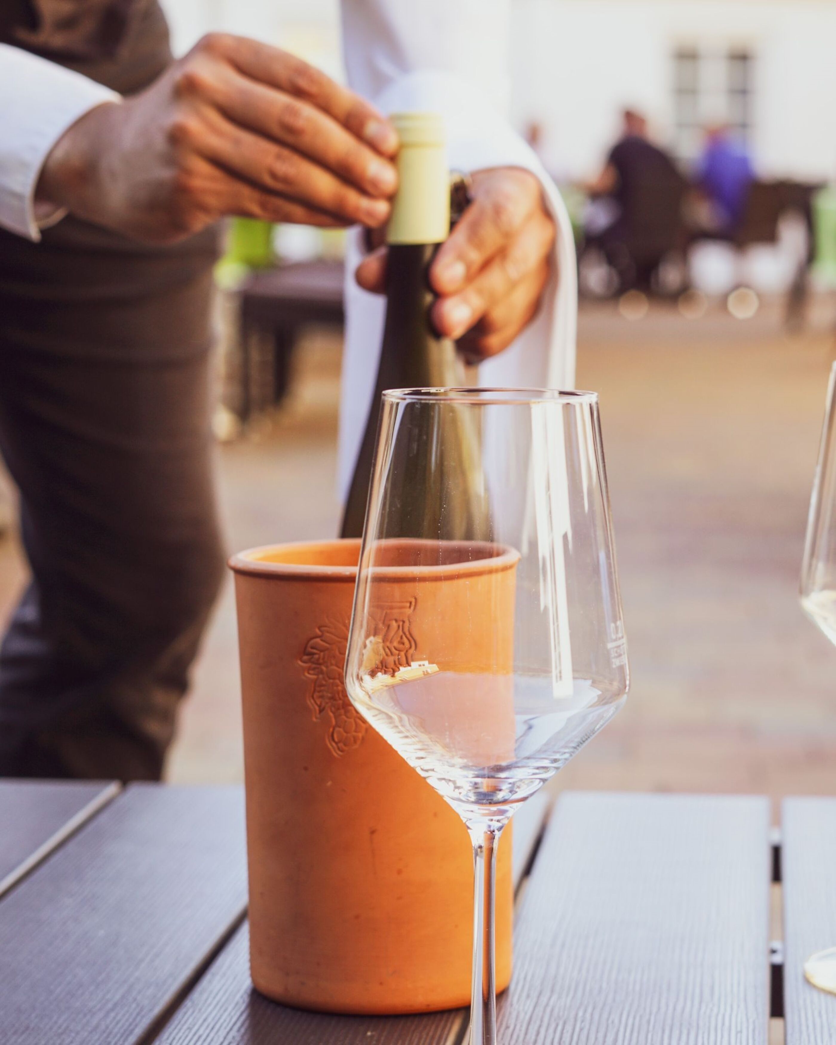 Ein Weinglas auf einem Tisch, daneben eine Terrakotta-Krug.