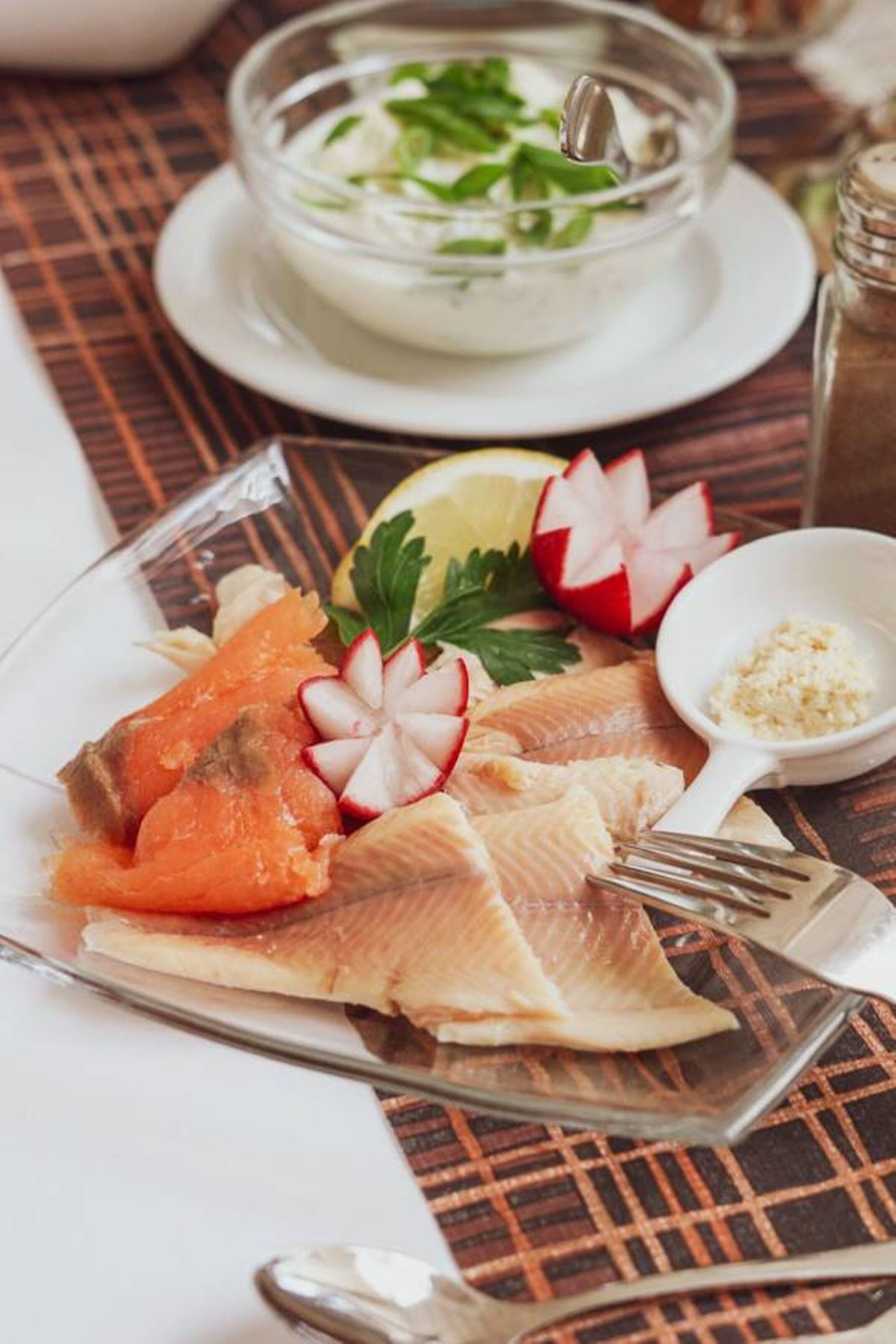 Un plato de salmón con rodajas de rábanos y limón sobre una mesa.
