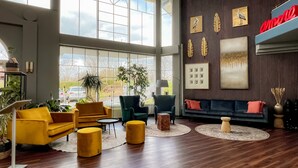 A spacious living area with large windows, a modern sofa set, and decorative wall art. - Atrium Hotel Amadeus (Osterfeld)