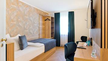 Habitación de hotel con cama, escritorio, silla, televisor y armario.