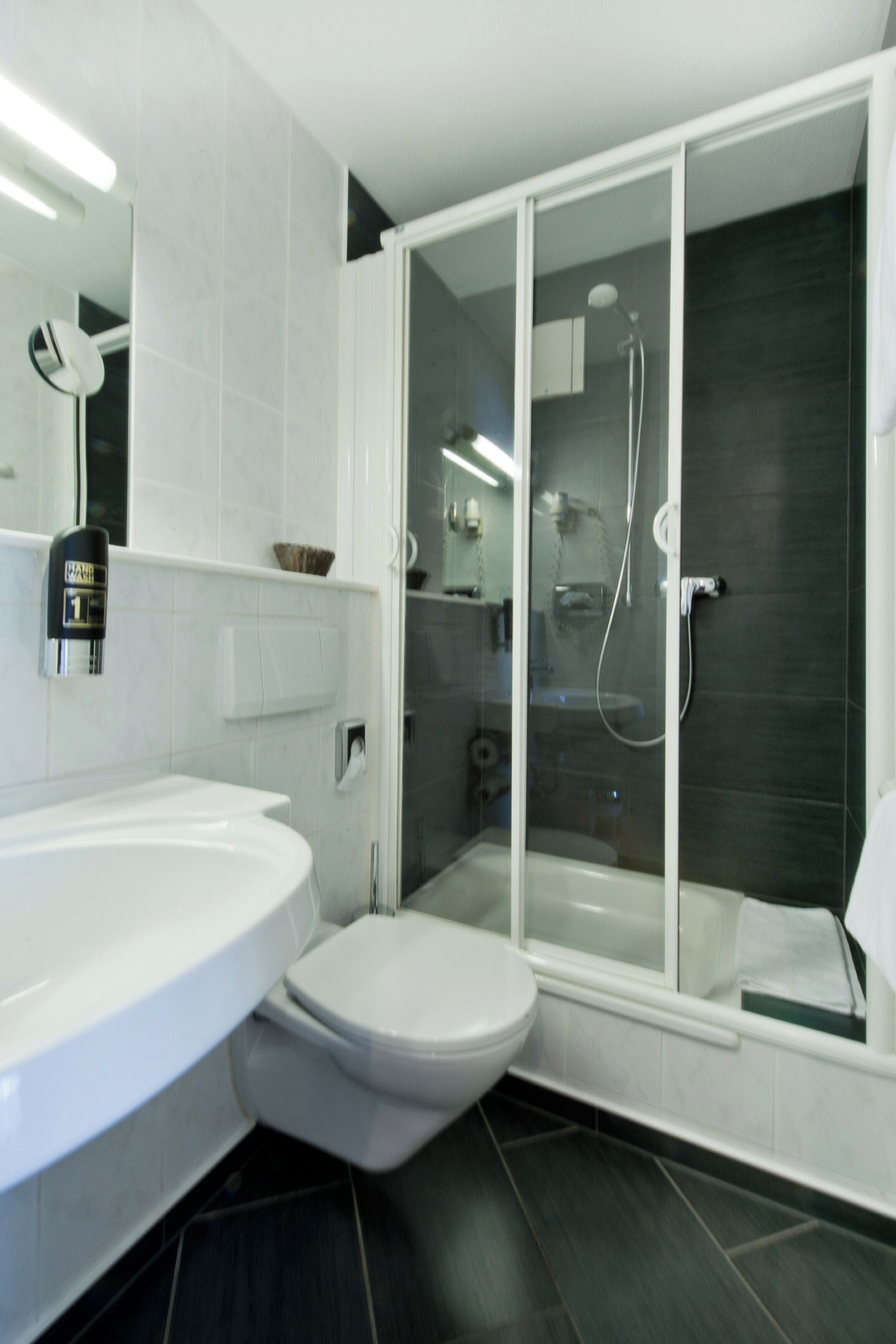 A modern bathroom with a white sink, toilet, and a glass-enclosed shower area.