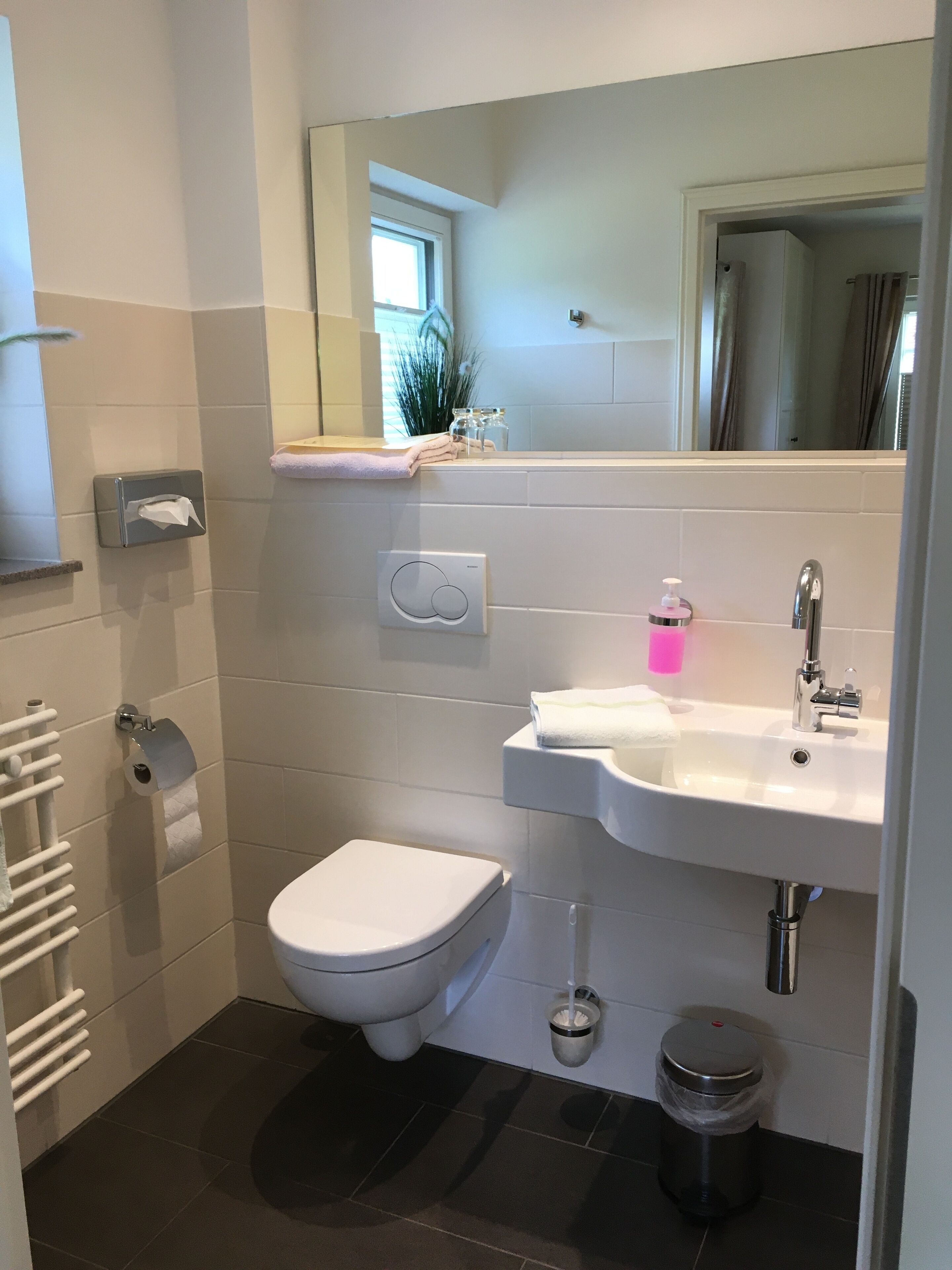 Une salle de bain moderne équipée de toilettes, d’un lavabo et d’un miroir.