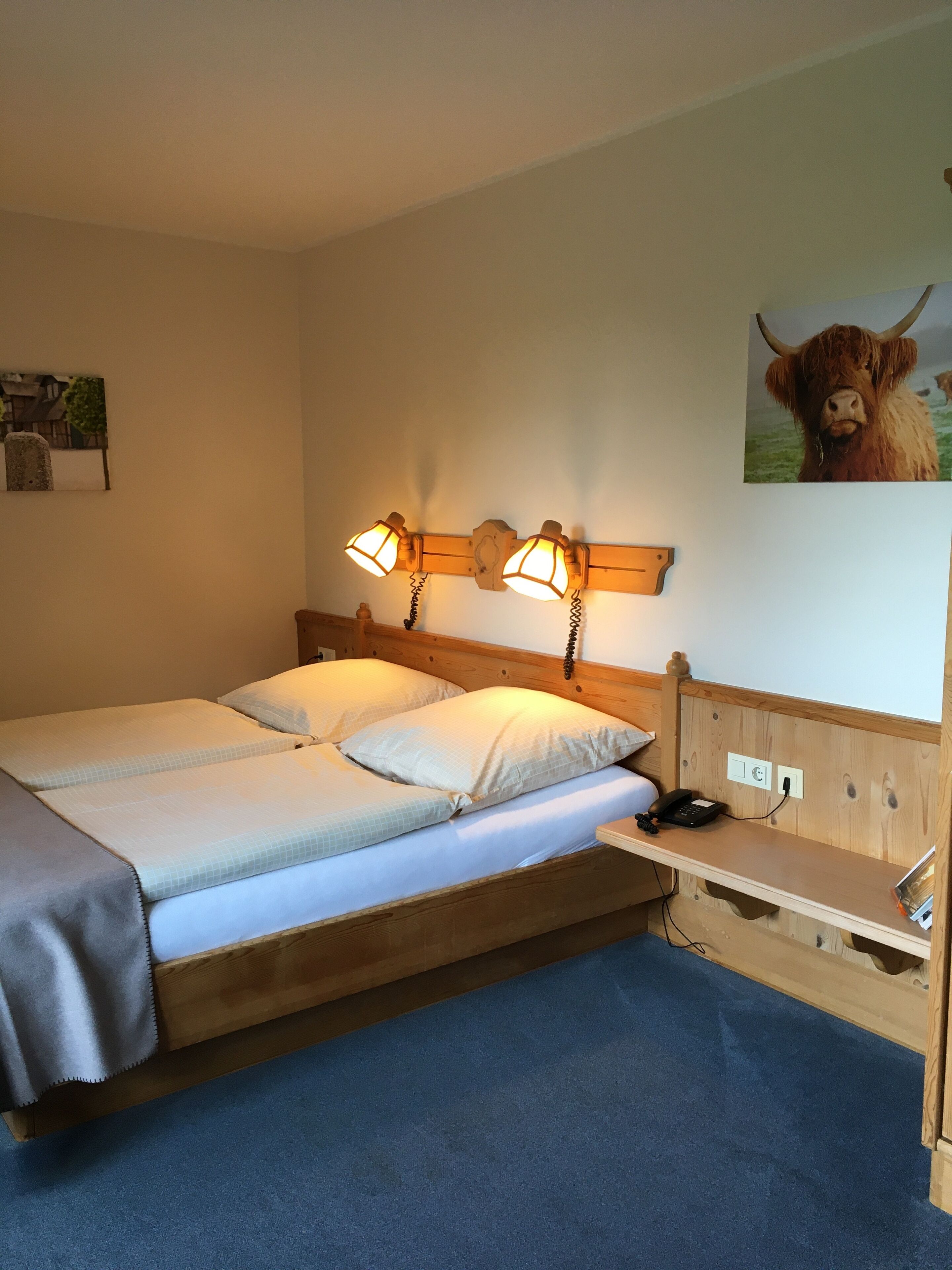 A double bed with two bedside tables, a wooden headboard, and a wall-mounted lamp.