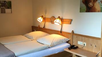 A double bed with two bedside tables, a wooden headboard, and a wall-mounted lamp.