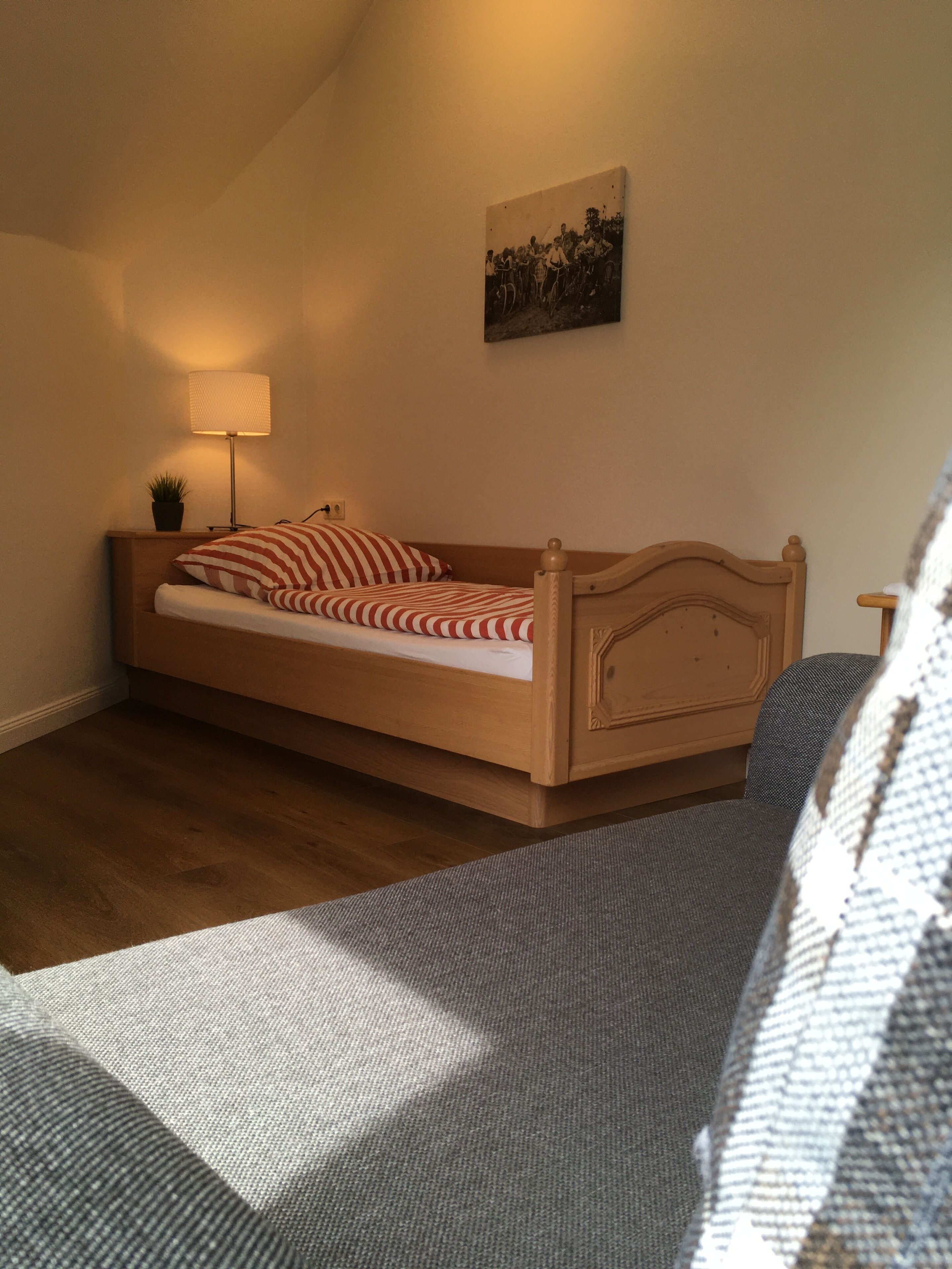 Una cama individual con cabecera de madera en una habitación con techo inclinado.
