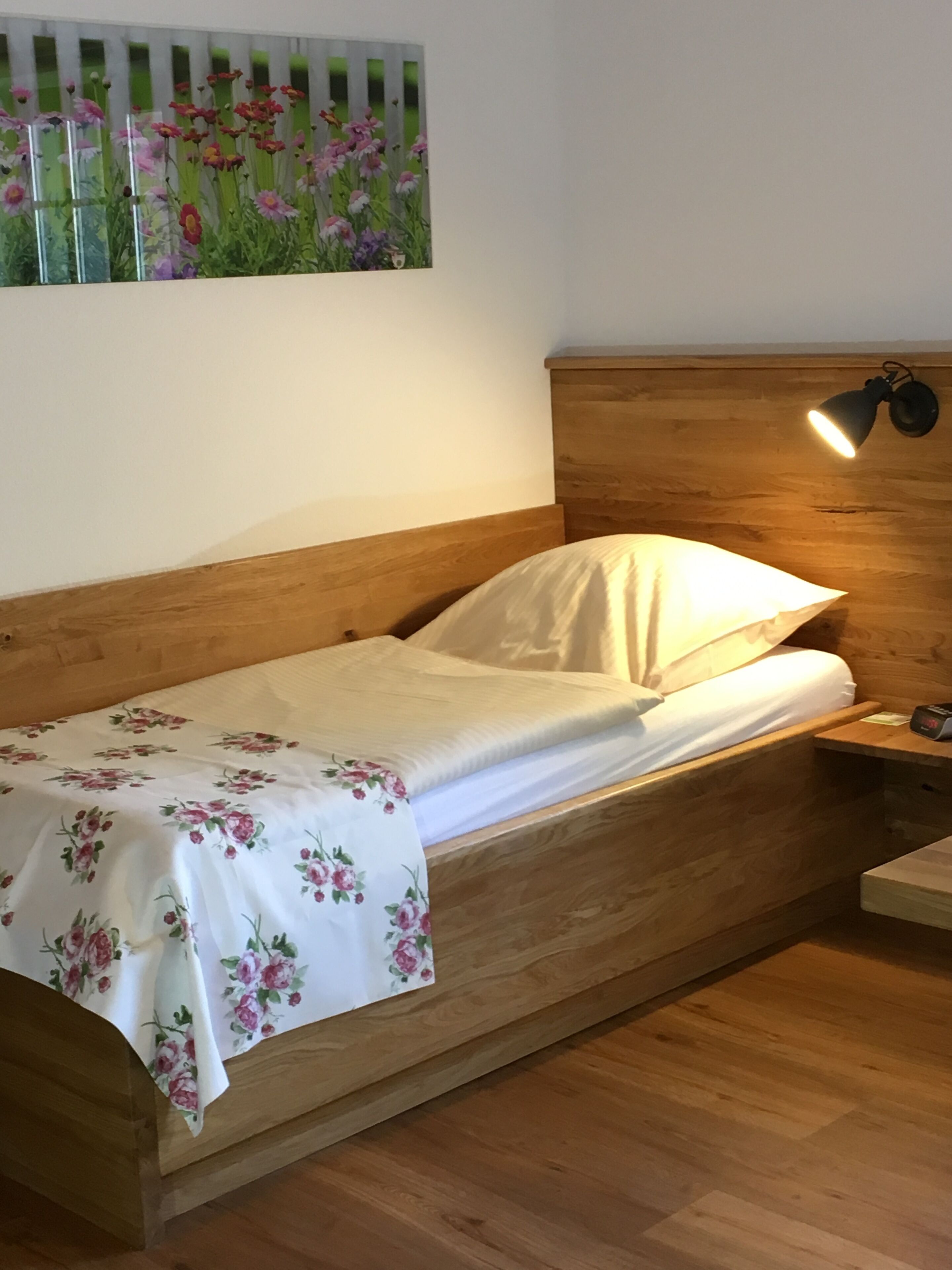 A single bed with a wooden headboard and a nightstand with a lamp.