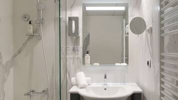 Un baño moderno con ducha envuelta en vidrio, una bañera independiente, un tocador con lavabo y un espejo.
