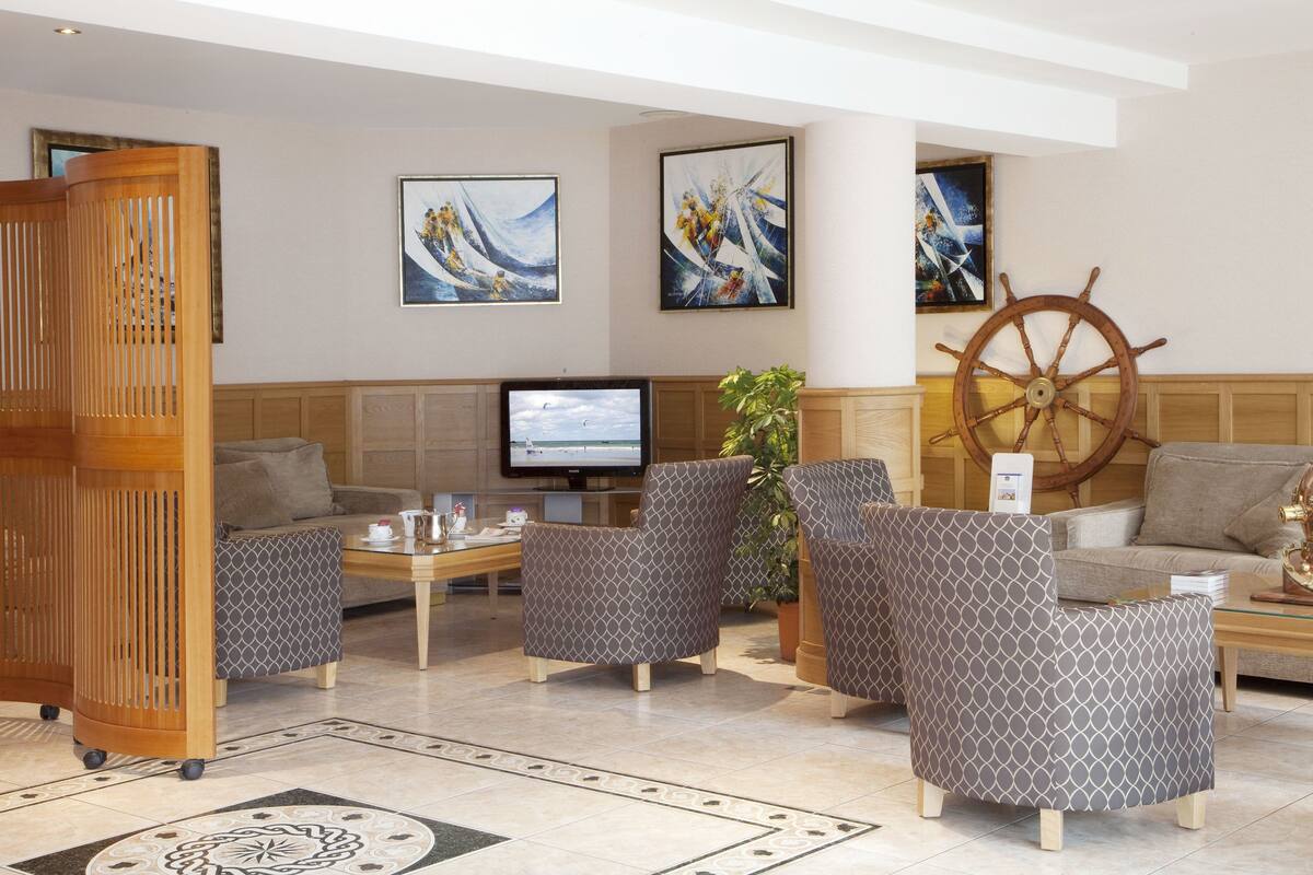 A lobby with seating, a television, artwork, and a ship's wheel.