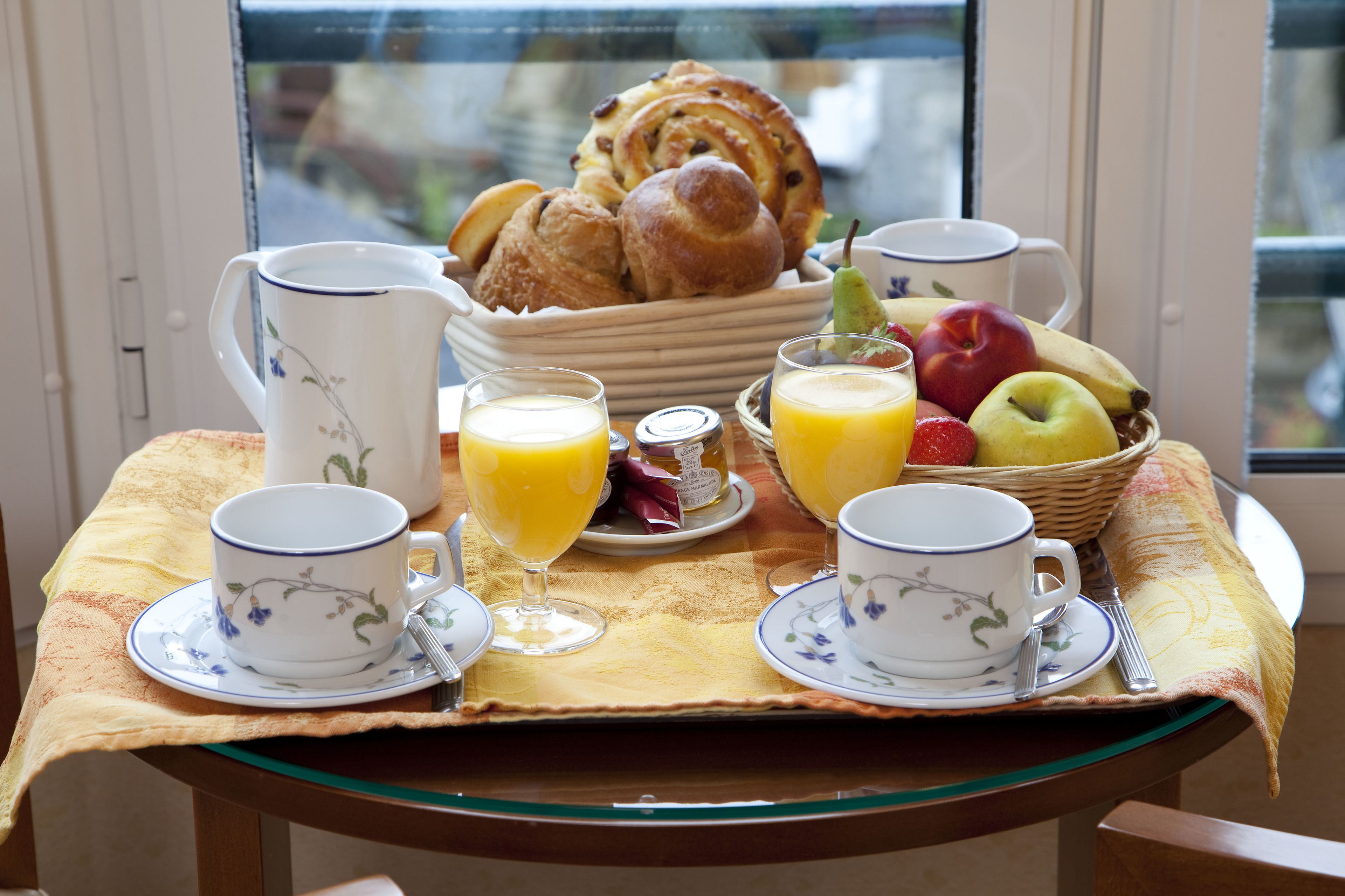 Une table de petit-déjeuner avec des viennoiseries, des fruits et des boissons.