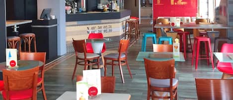 A restaurant with multiple tables and chairs, a counter with a menu, and a large number '142' on the wall.
