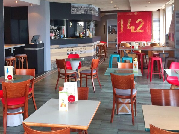 Un restaurante con varias mesas y sillas, una barra con un menú, y el número grande 142 en la pared.
