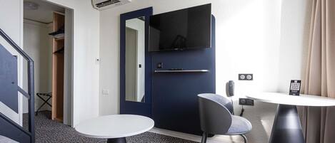 A modern living room with a sofa, a round table, a chair, and a TV mounted on a dark blue door.