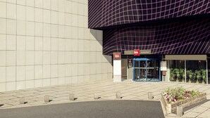 En moderne bygning med en facade i et gridmønster og en markant, buet glaskonstruktion.