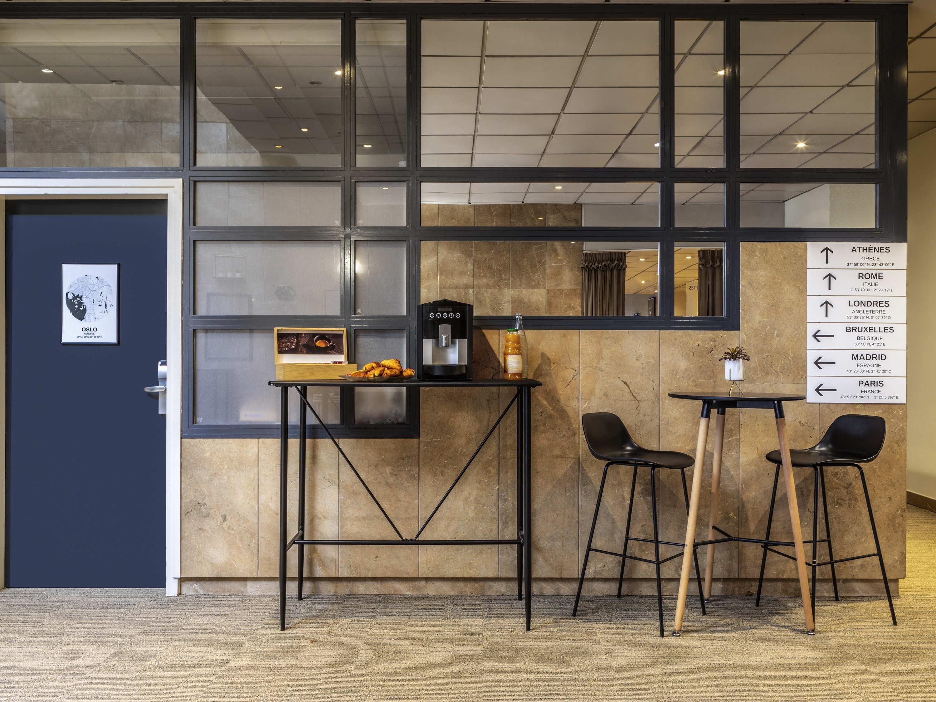 A modern interior with a coffee station, two chairs, and a directional sign.